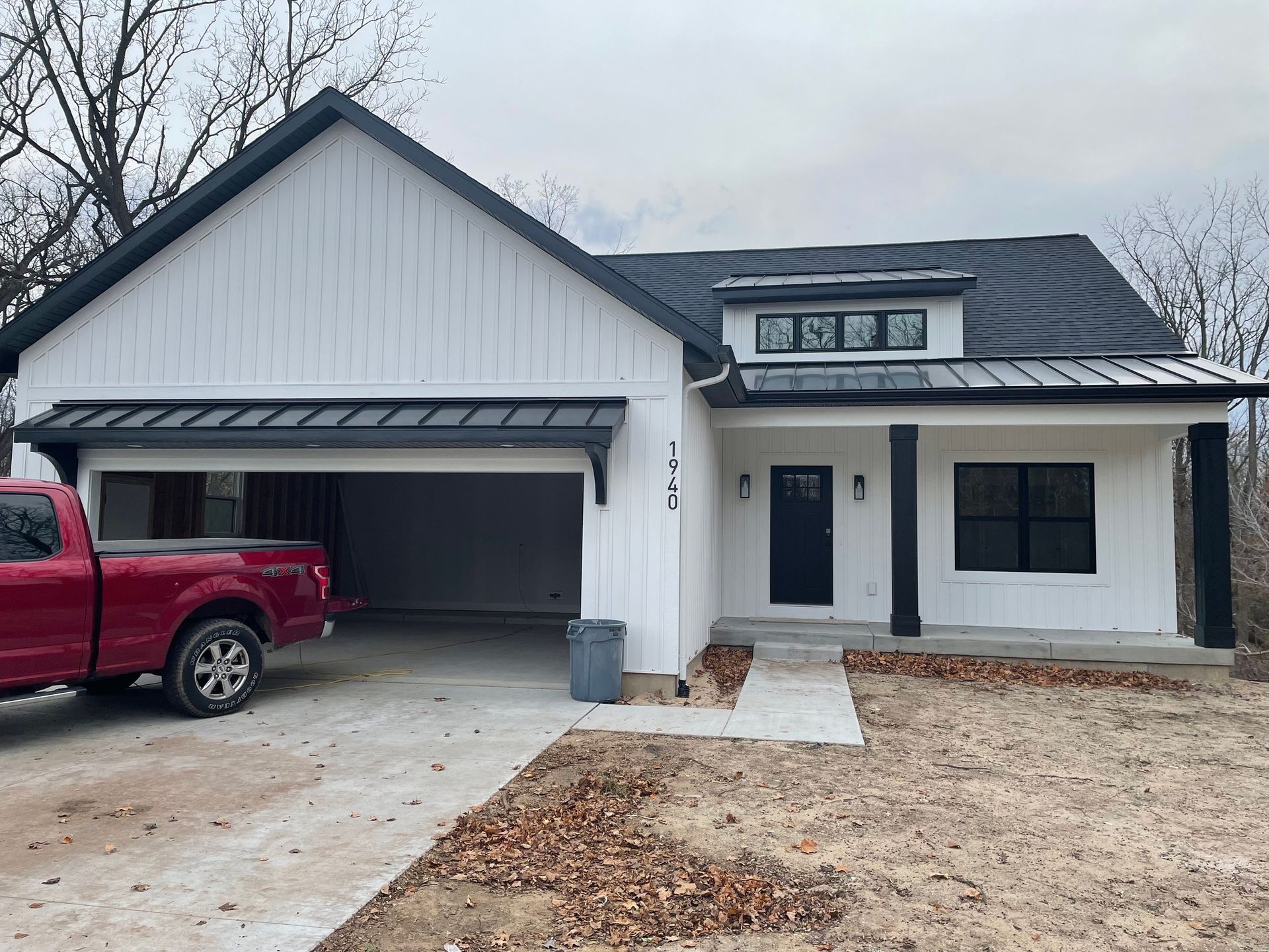 A red truck is parked in front of a white house.