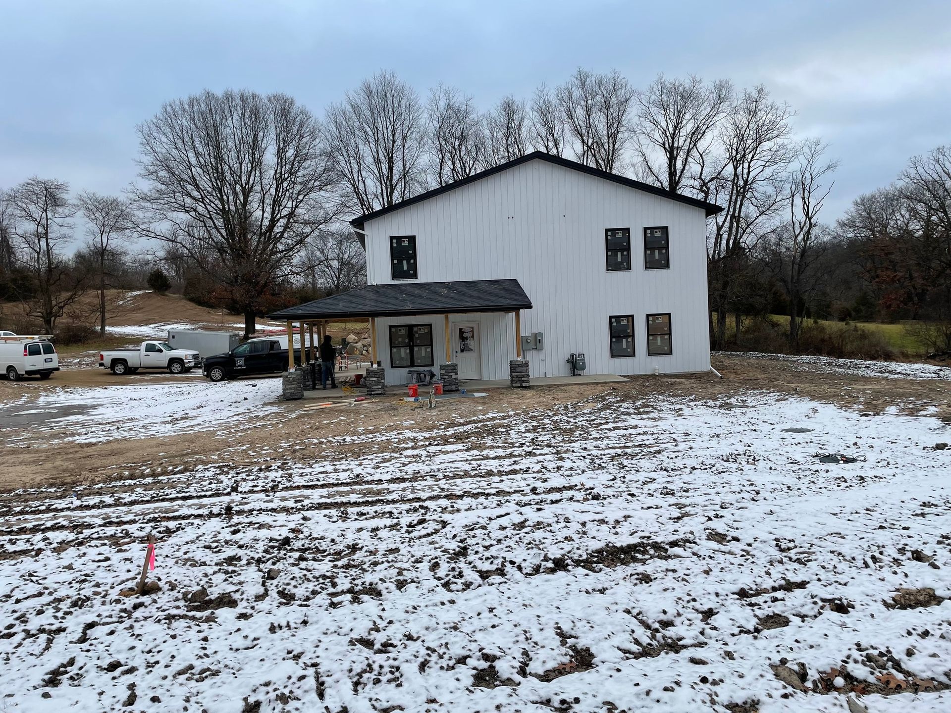 A large white house is sitting in the middle of a snowy field.