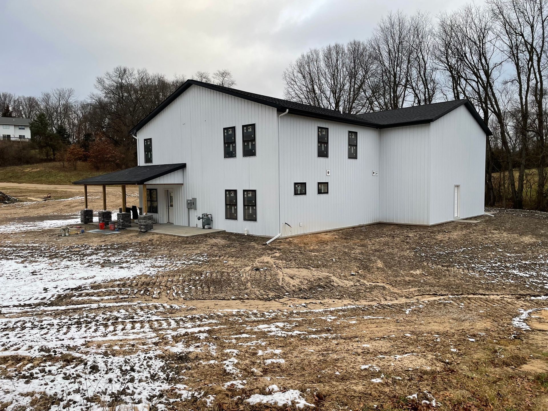 A large white house is sitting in the middle of a snowy field.