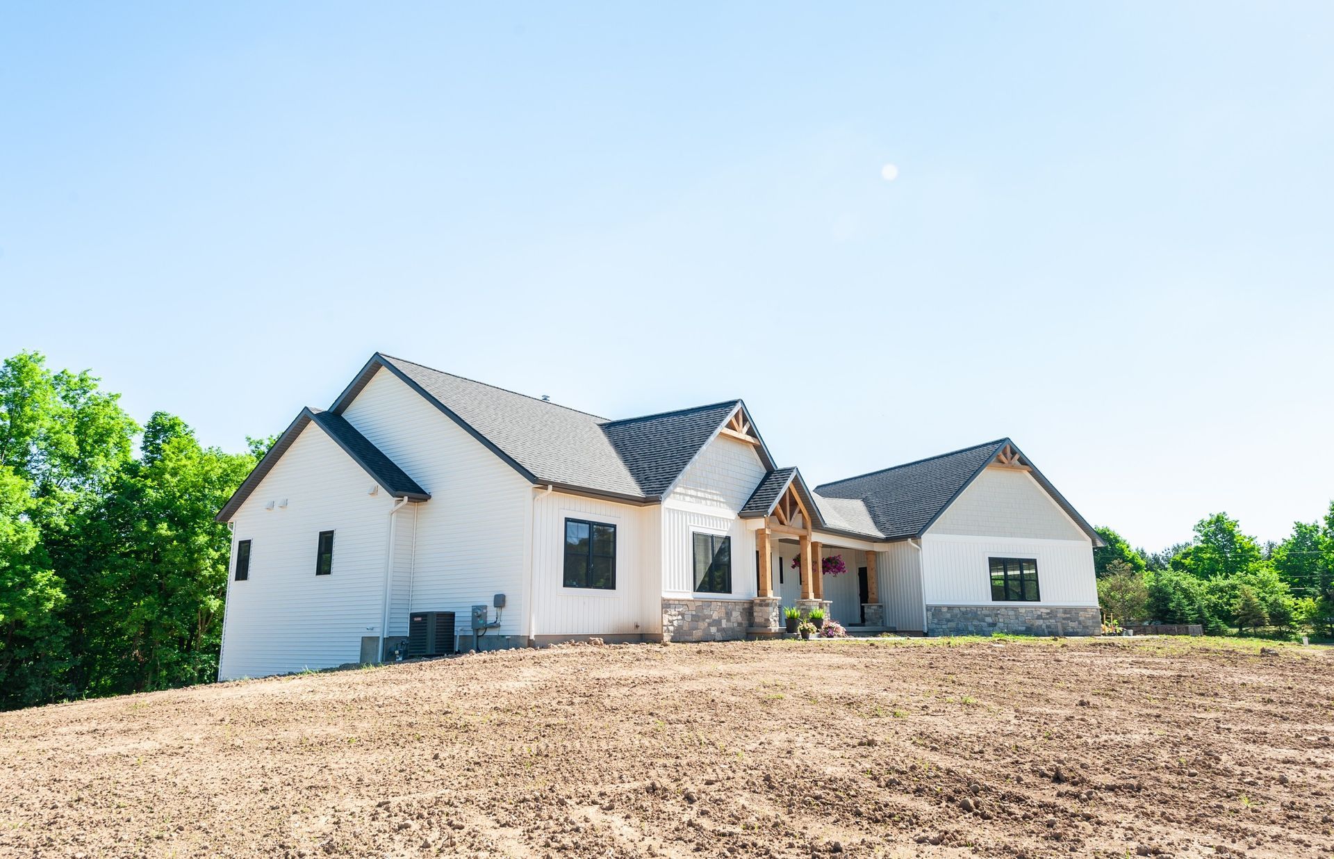 A large white house is sitting on top of a dirt hill.