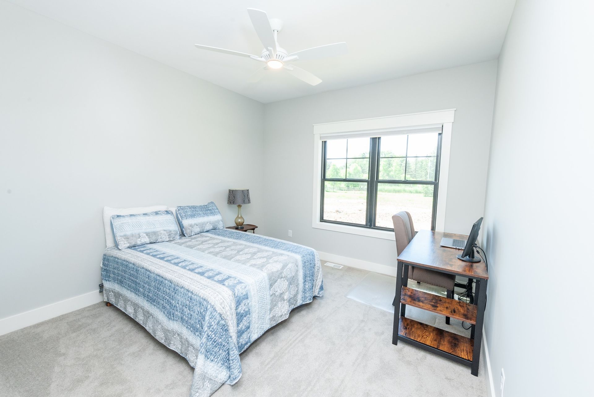A bedroom with a bed , desk , and ceiling fan.