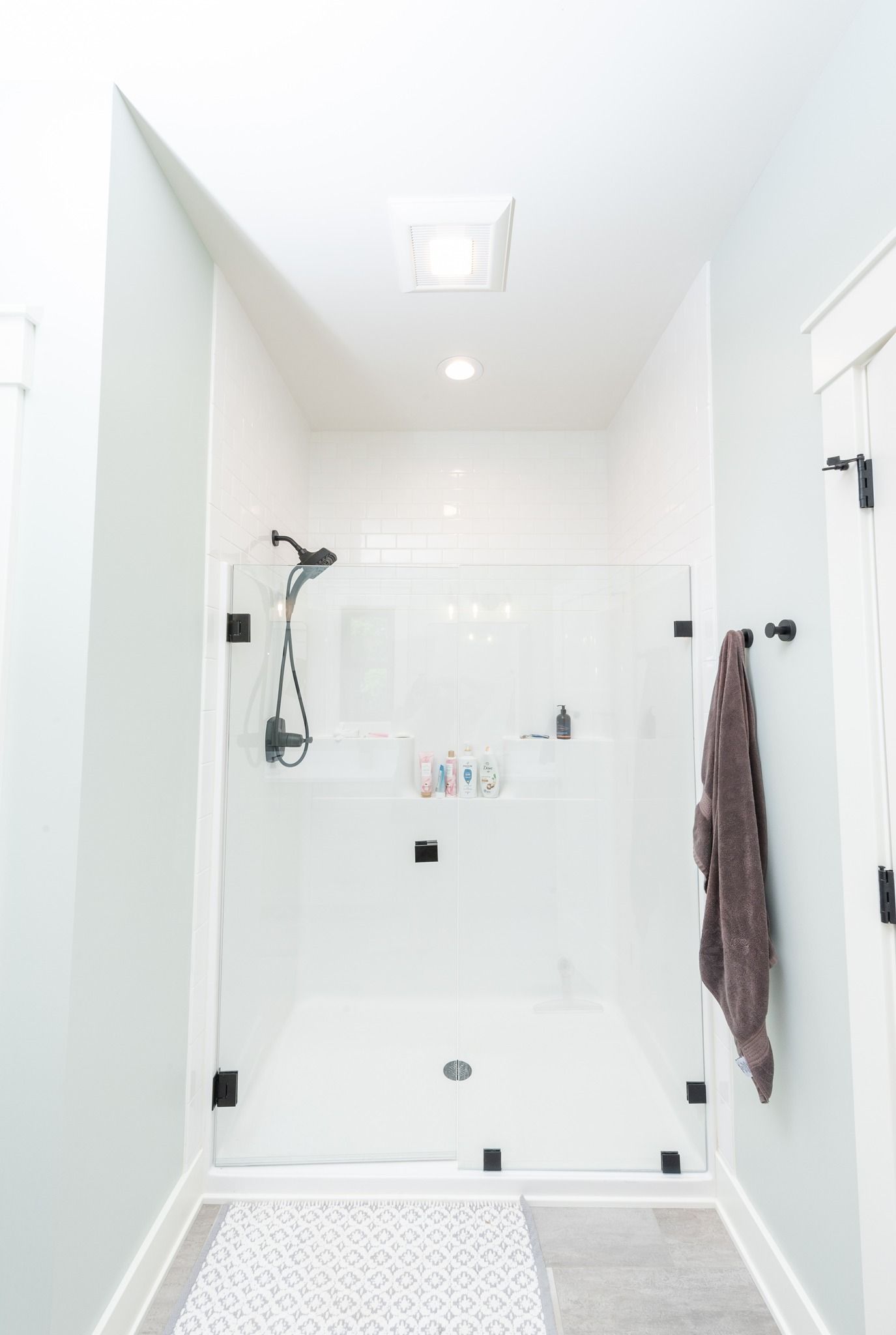 A bathroom with a walk in shower and a towel hanging on the wall.