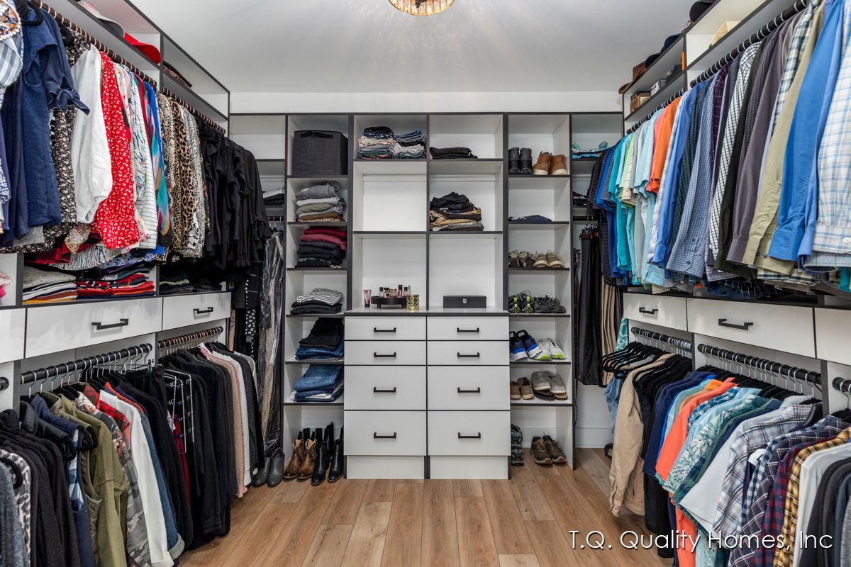 A walk in closet filled with lots of clothes and shoes.