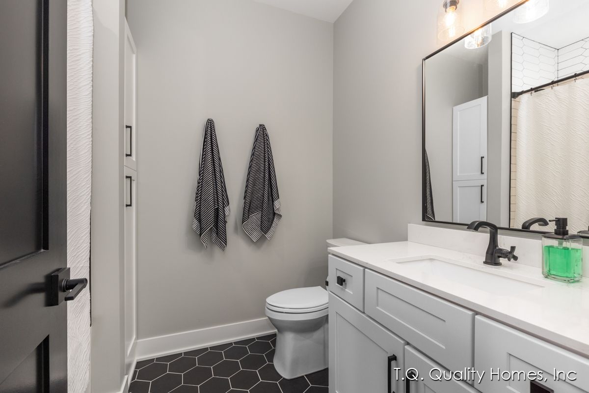 A bathroom with a toilet , sink , mirror and towels hanging on the wall.