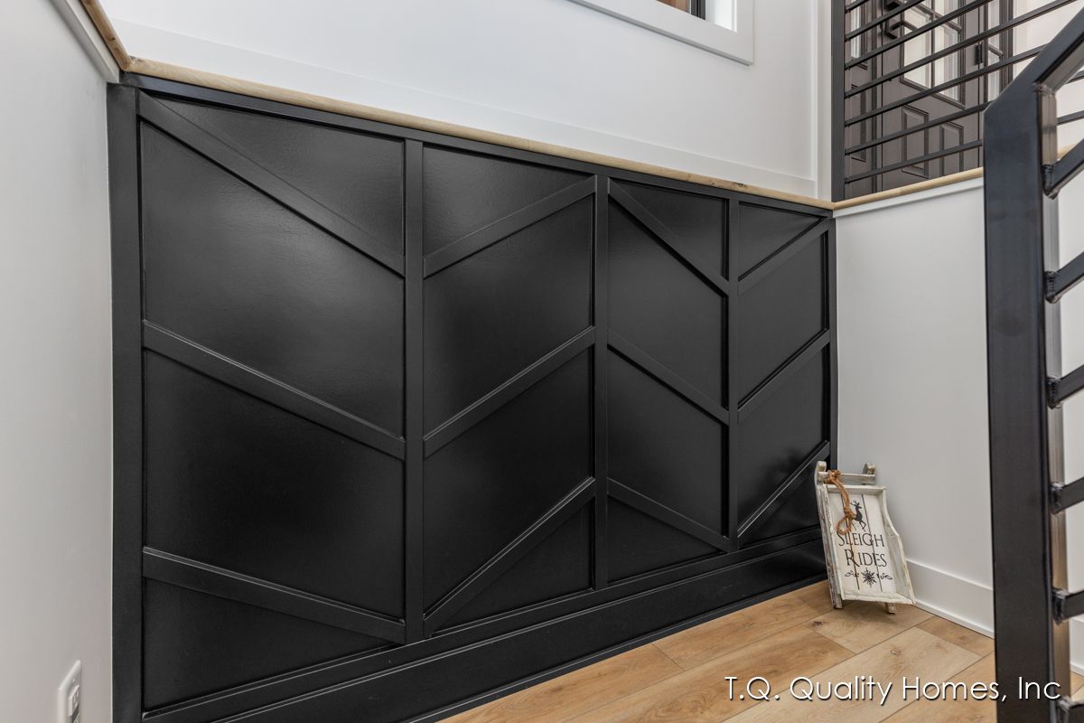 A black wall with a geometric pattern on it is next to a staircase.