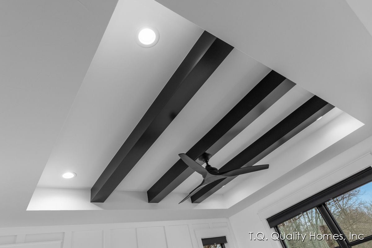 A ceiling with black beams and a ceiling fan