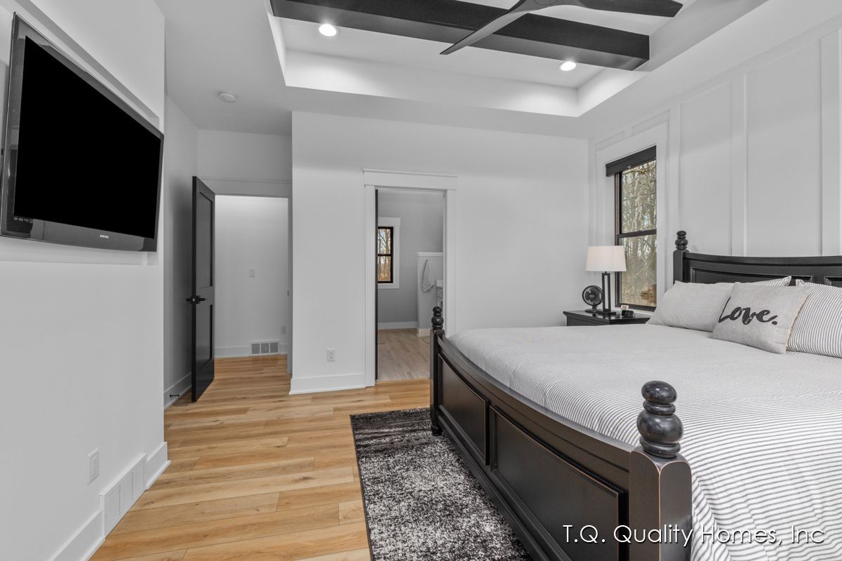 A bedroom with a large bed and a flat screen tv on the wall.