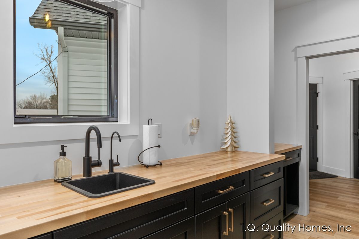A kitchen with a sink , cabinets , and a window.