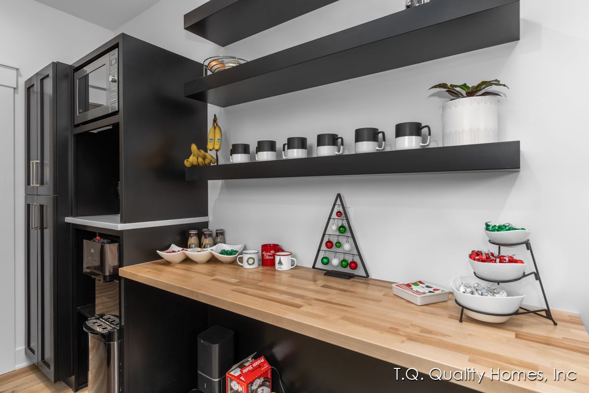 A kitchen with a wooden counter top and black shelves.