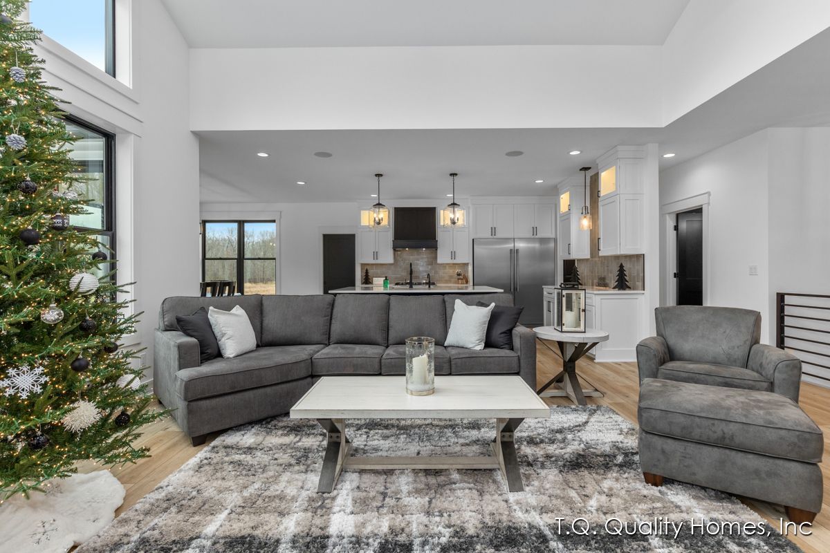 A living room with a couch , chair , coffee table and a christmas tree.