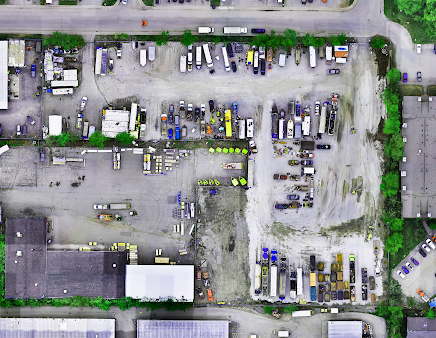 Aerial view of a commercial lot with trucks, storage containers, and construction equipment.