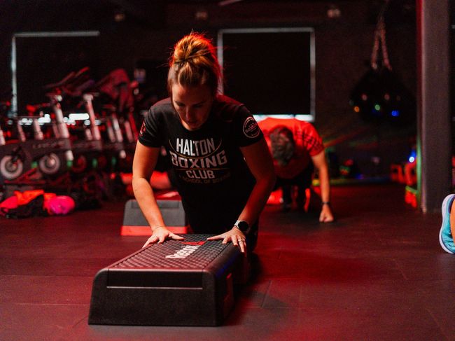 a woman is doing push ups on a step platform in a gym .