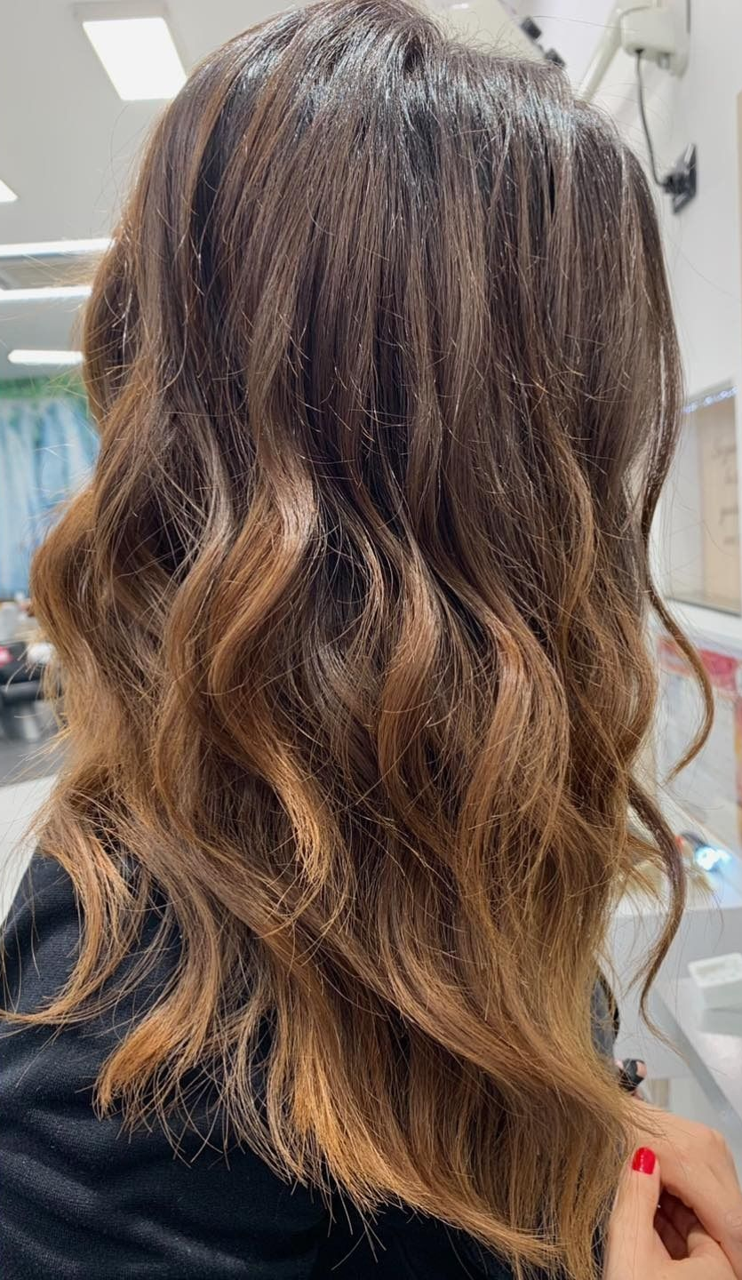 Cuoco in camice bianco e grembiule a righe, mentre mescola il cibo in una padella con un mestolo in cucina.