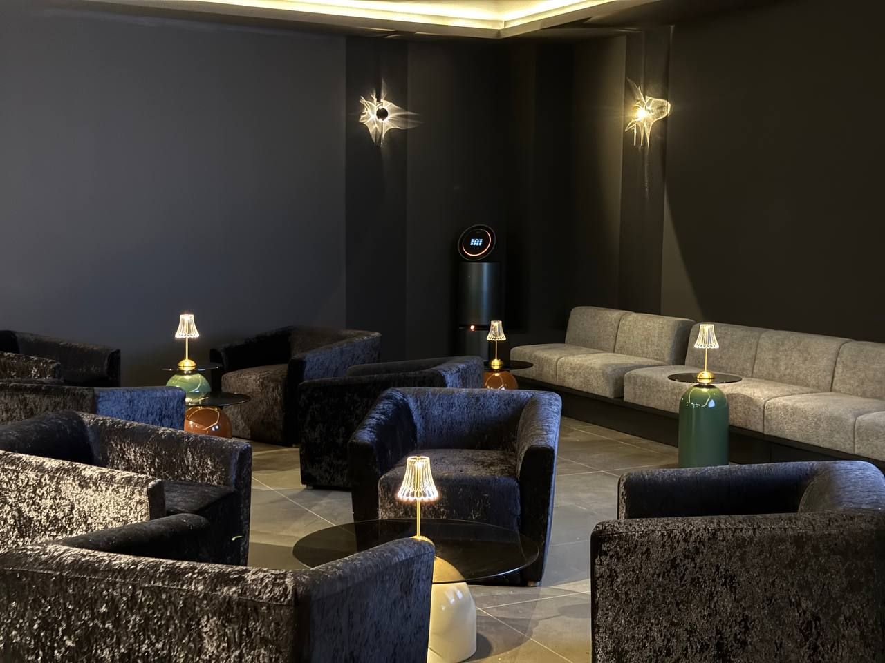 Modern lobby featuring white marble floors, a curved beige sofa, armchairs, a reception desk, and a burgundy accent wall.