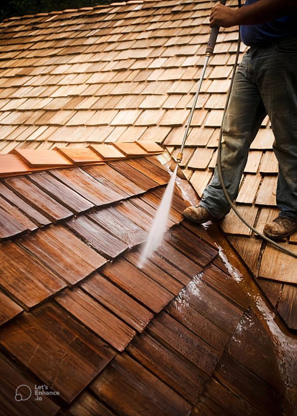 A man is cleaning a tiled roof in Newport, Wales with a soft pressure washer. Expertly removing moss.