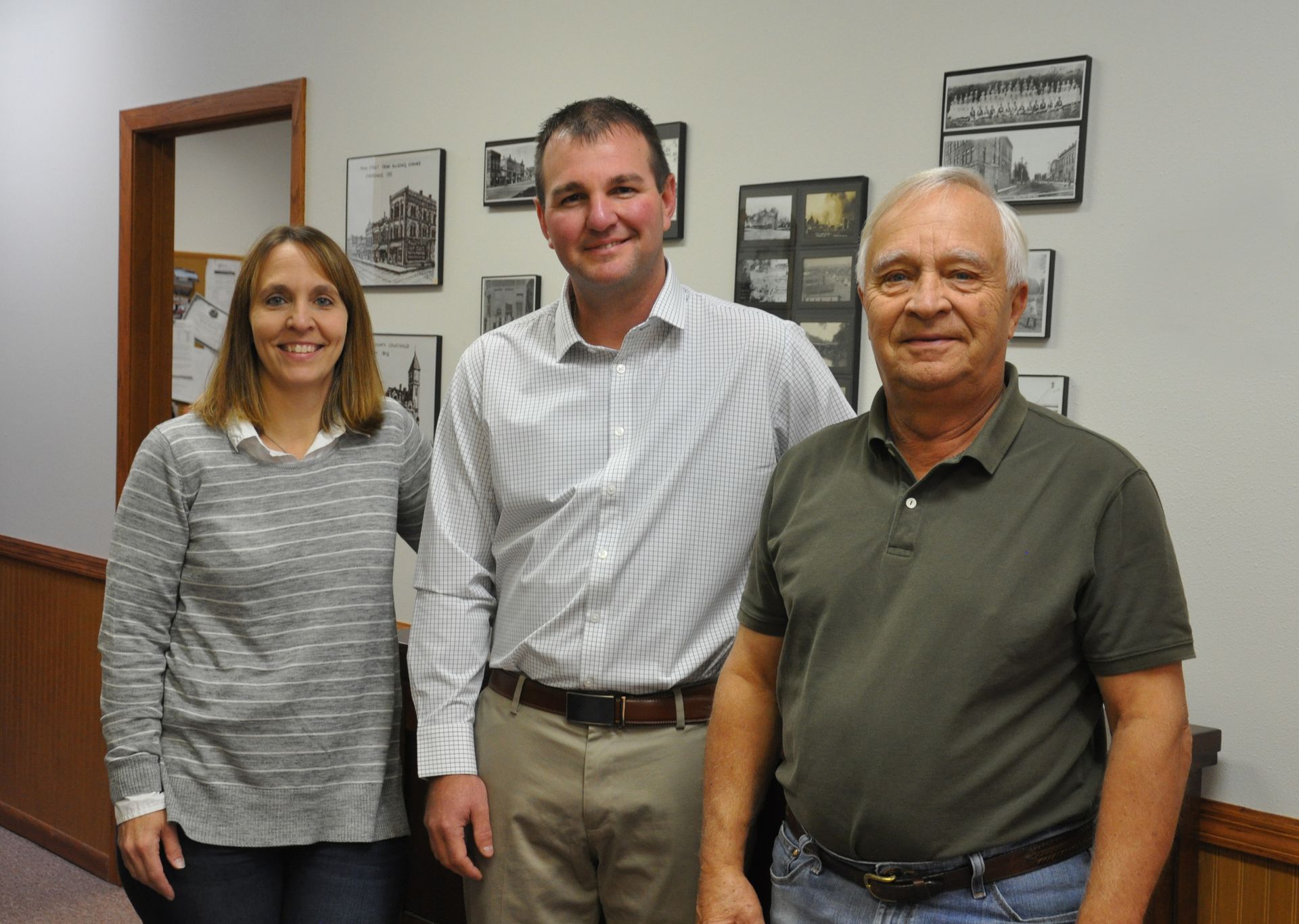 Three people are posing for a picture in a hallway.