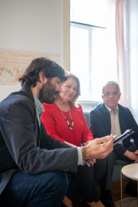 A group of people are sitting on a couch looking at a tablet.