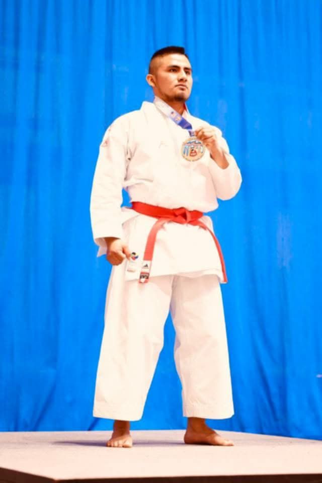 A man in a karate uniform is holding a medal