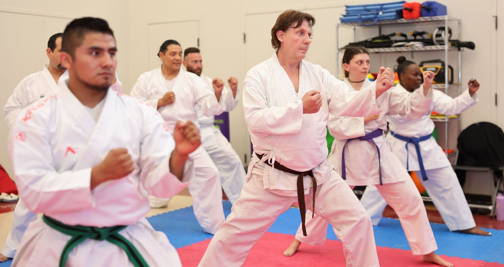 A group of people are practicing karate in a gym.