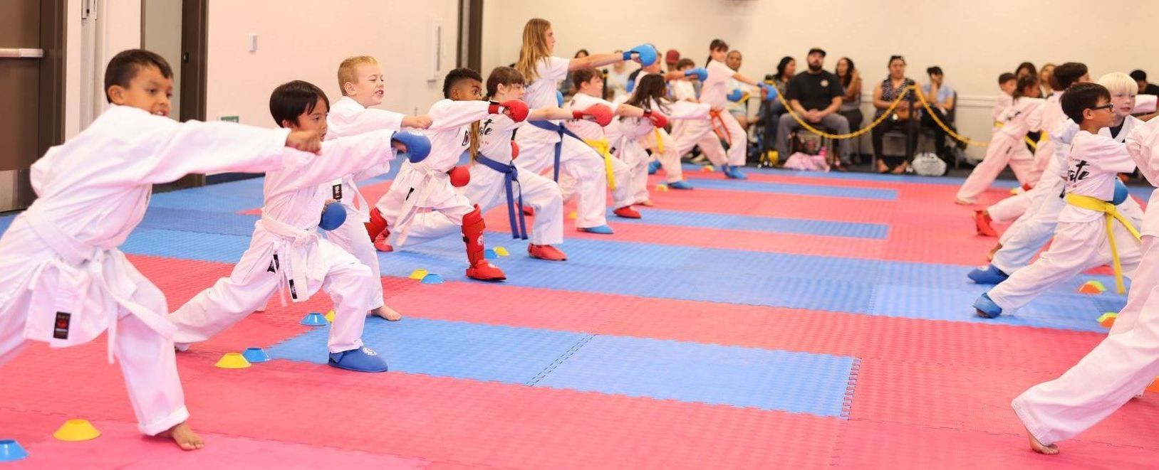 A group of children are practicing karate in a gym.