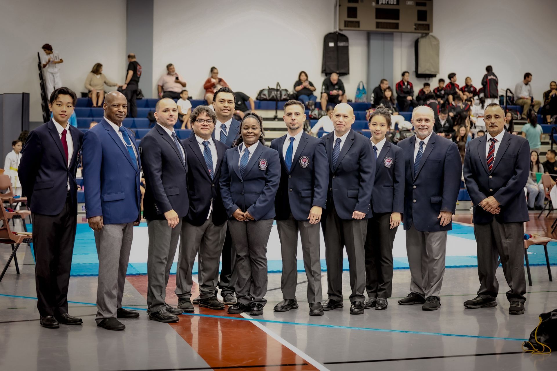Group of referees in suits at a sporting event, standing in a gym.