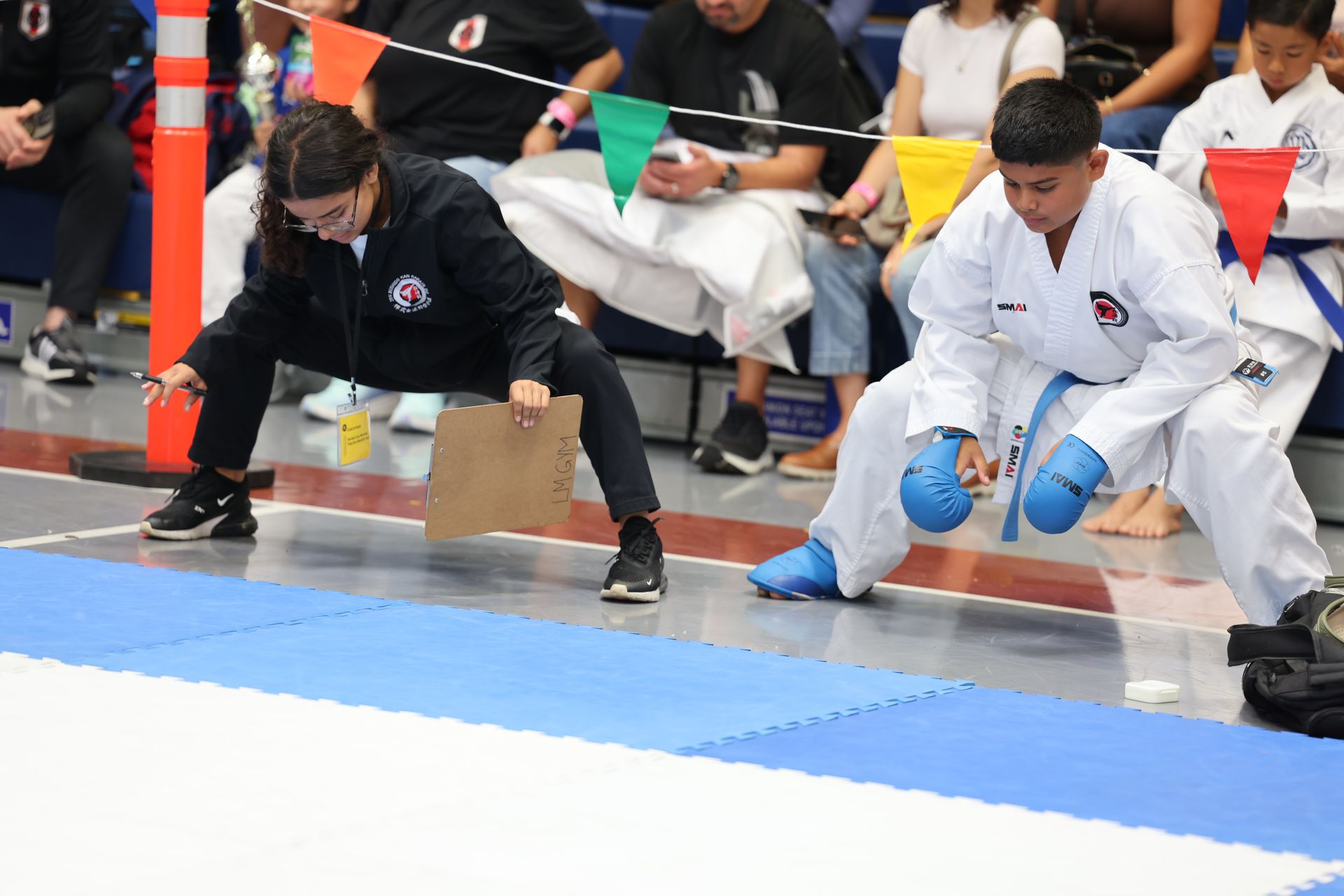 Karate competitor in blue gi and coach at a competition.