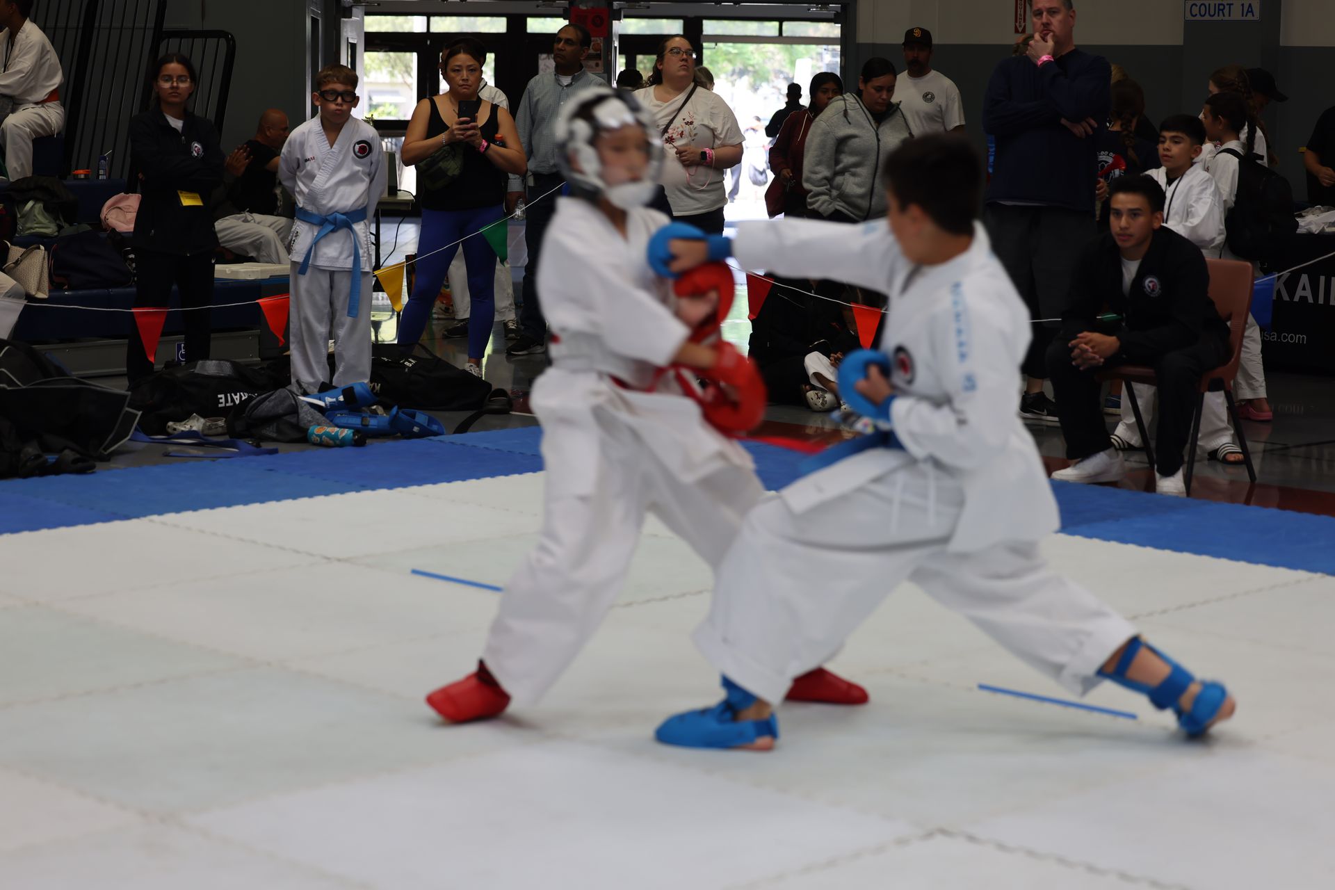 Two young karate students in white uniforms sparring in a competition.