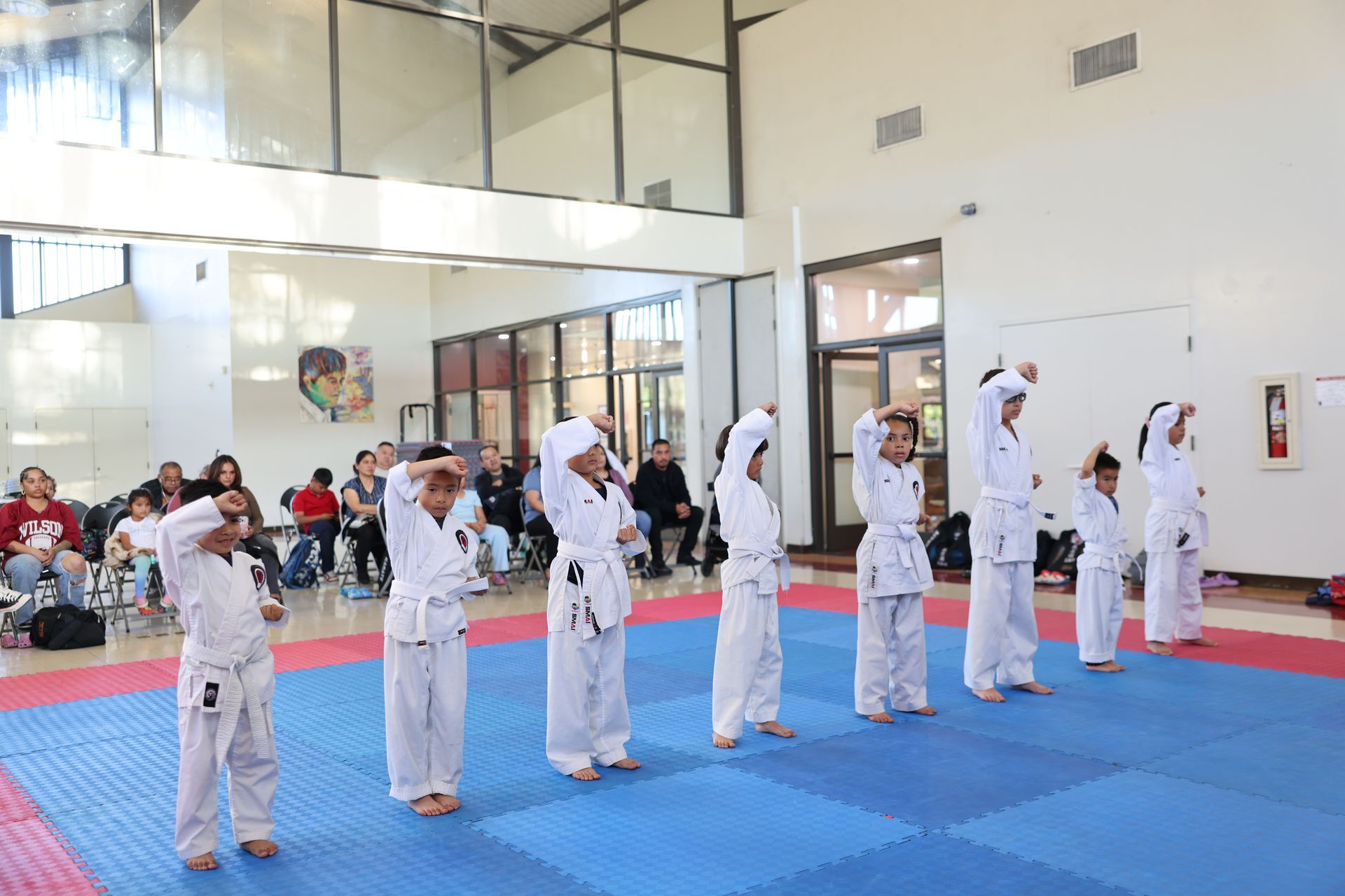 A group of children are practicing martial arts in a gym.