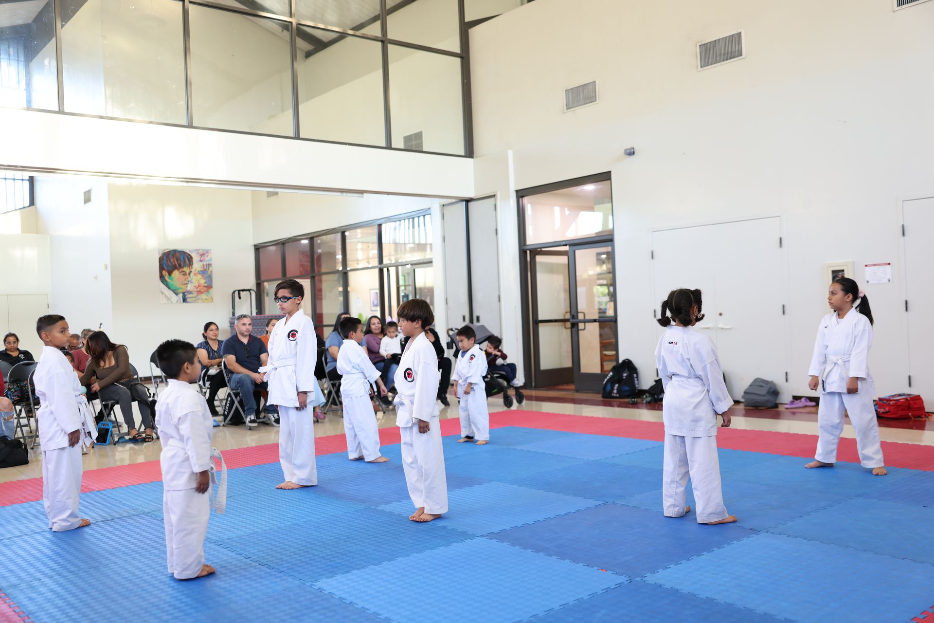 A group of children are practicing martial arts in a gym.