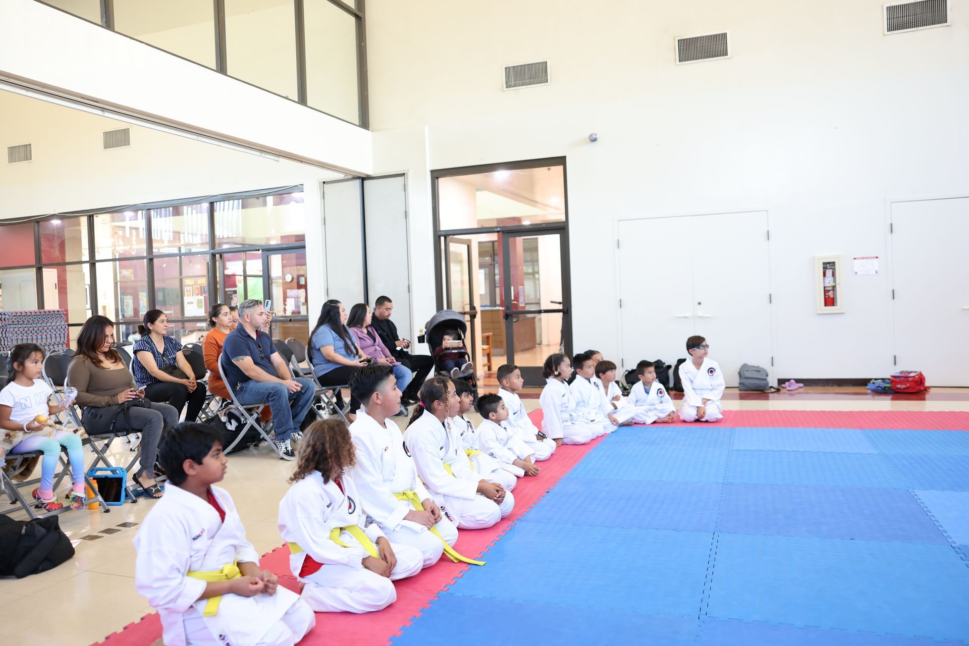 A group of children are sitting on the floor in a gym.