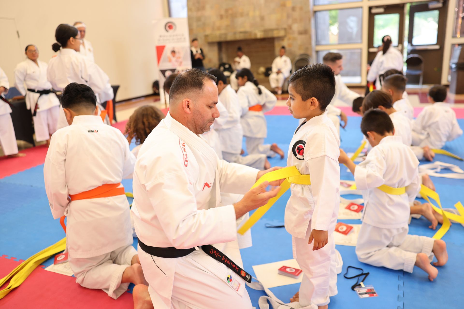 A man is helping a young boy with his karate belt.