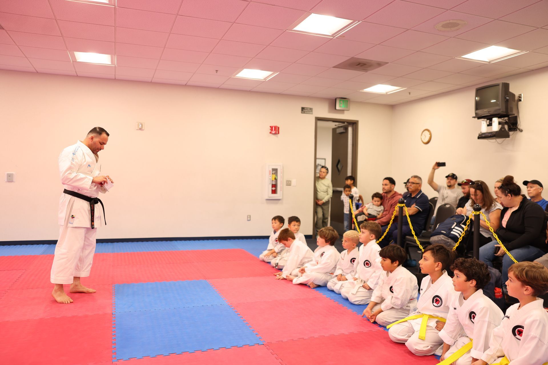 A group of children are sitting on the floor in a karate class.