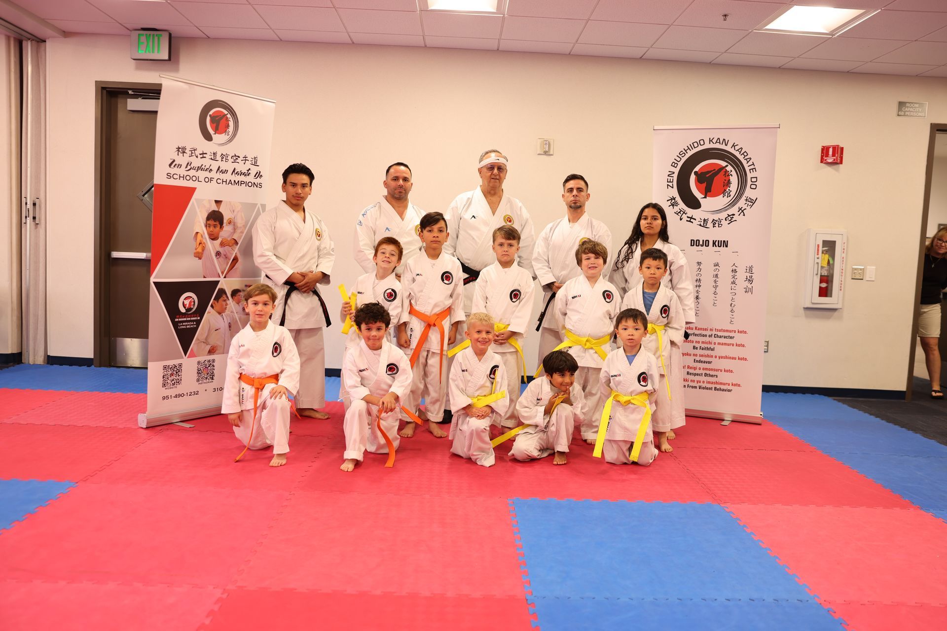 A group of people in karate uniforms are posing for a picture in a gym.