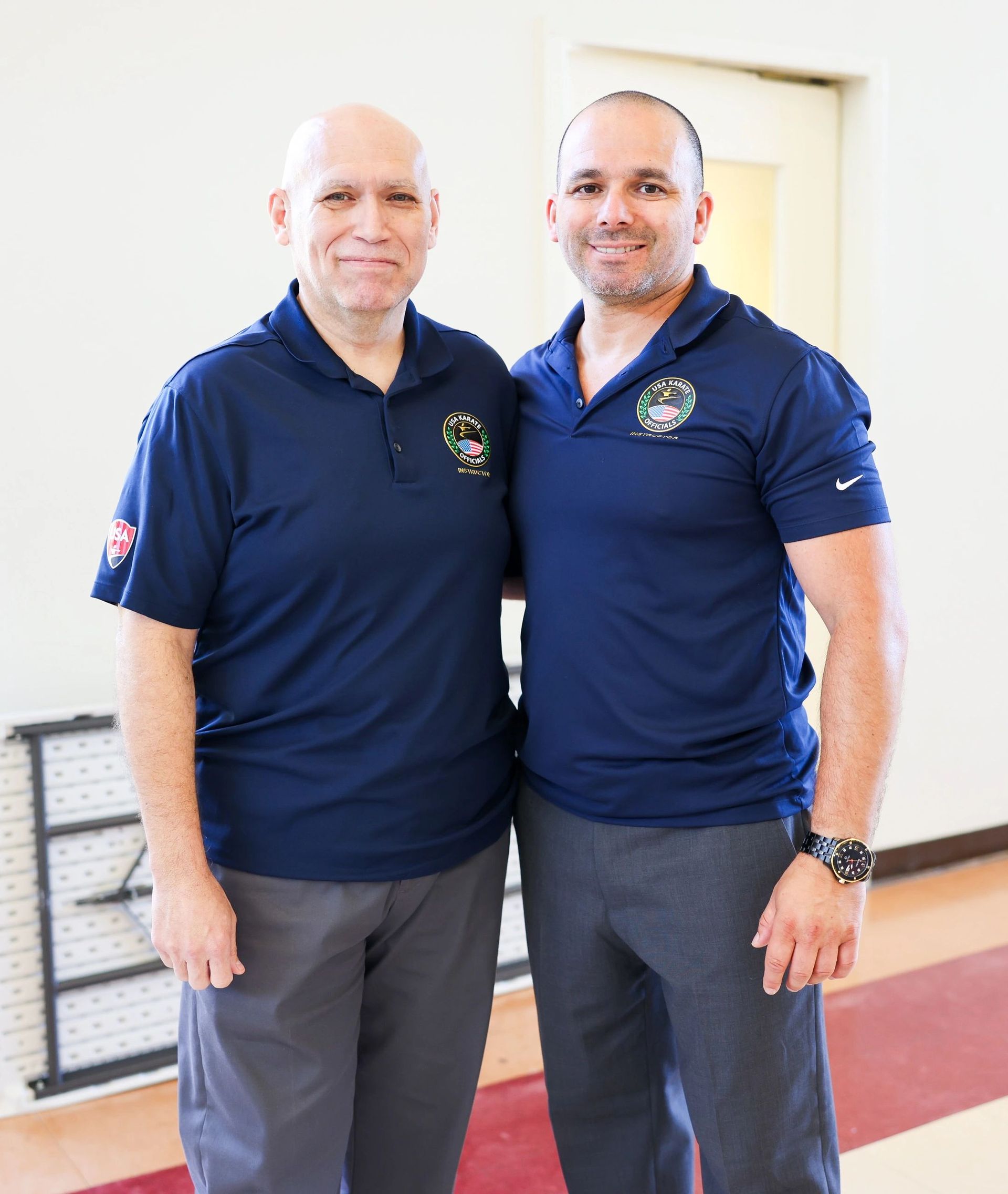 Two men standing next to each other wearing blue shirts