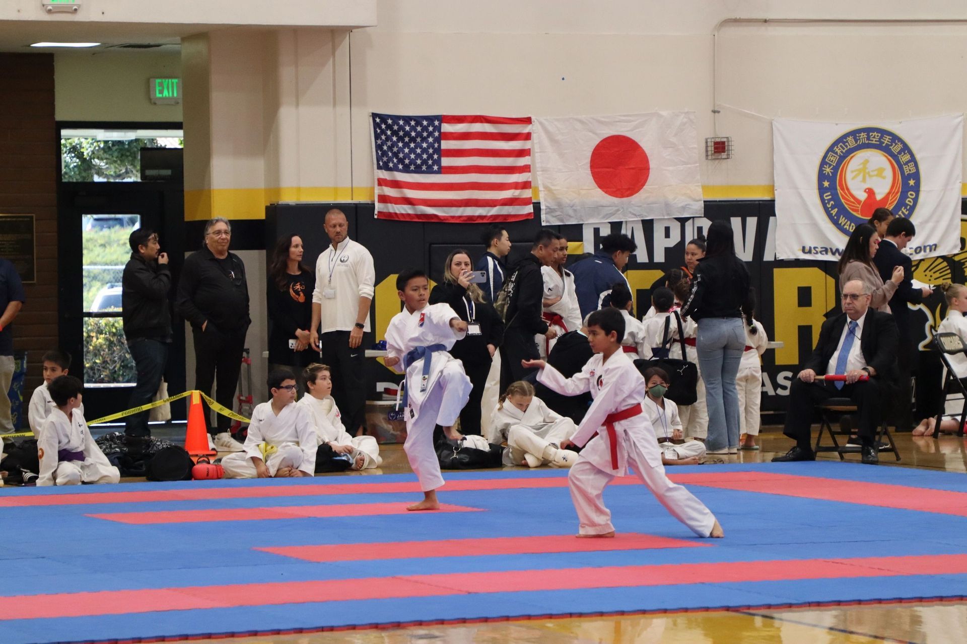 A group of kids are practicing martial arts in a gym.