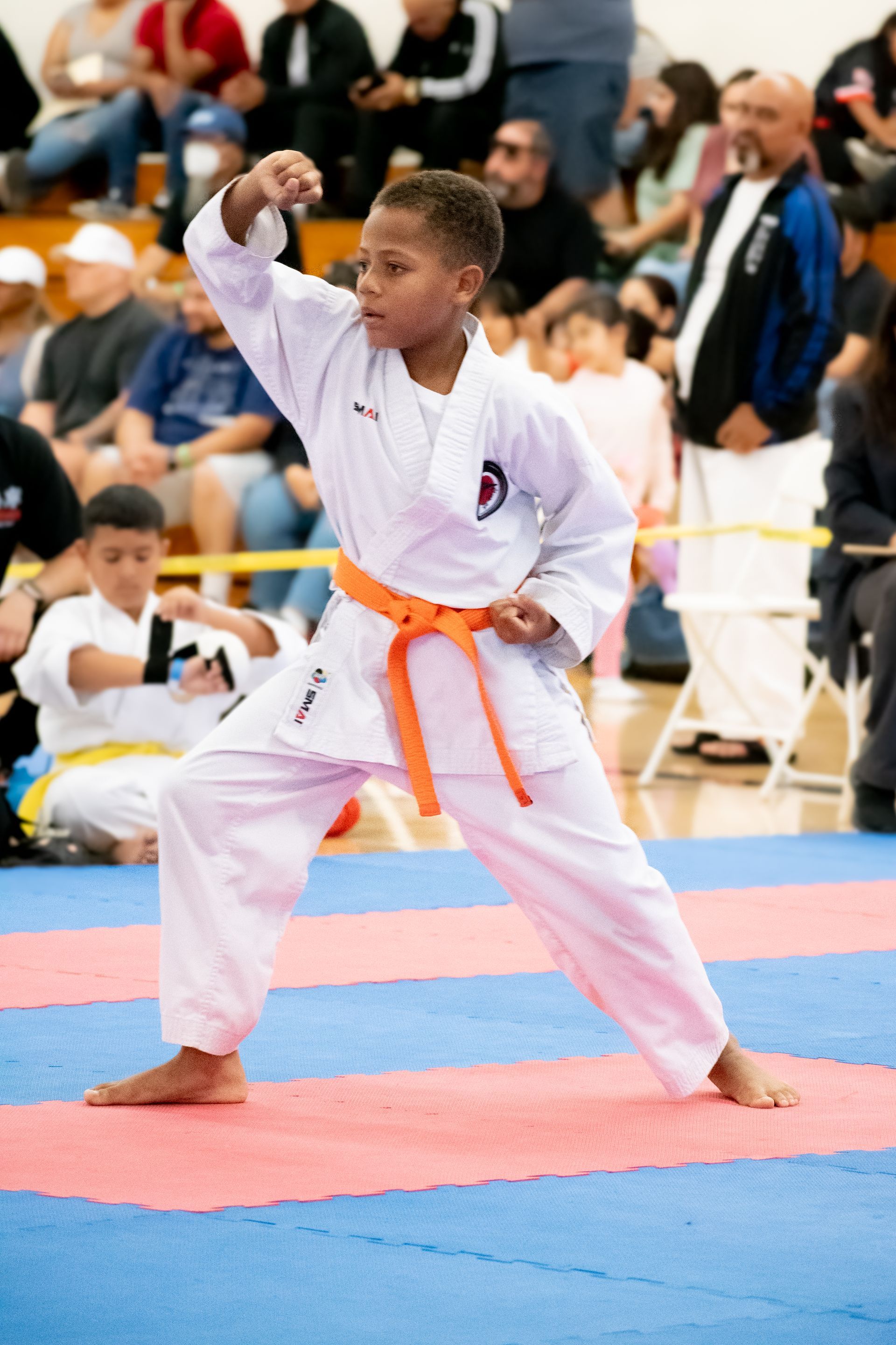 A young boy in a white karate uniform with an orange belt