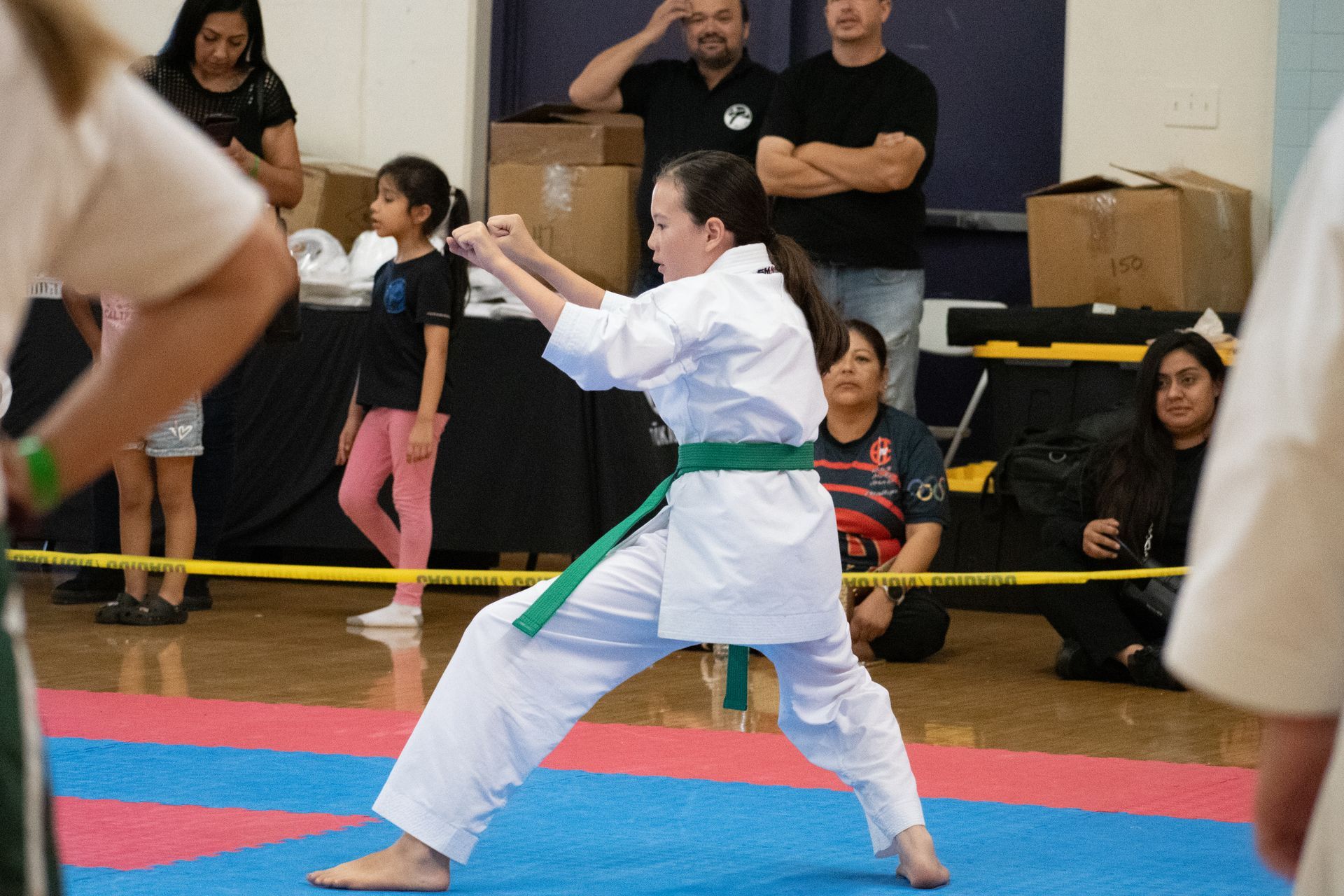 A woman in a white karate uniform with a green belt