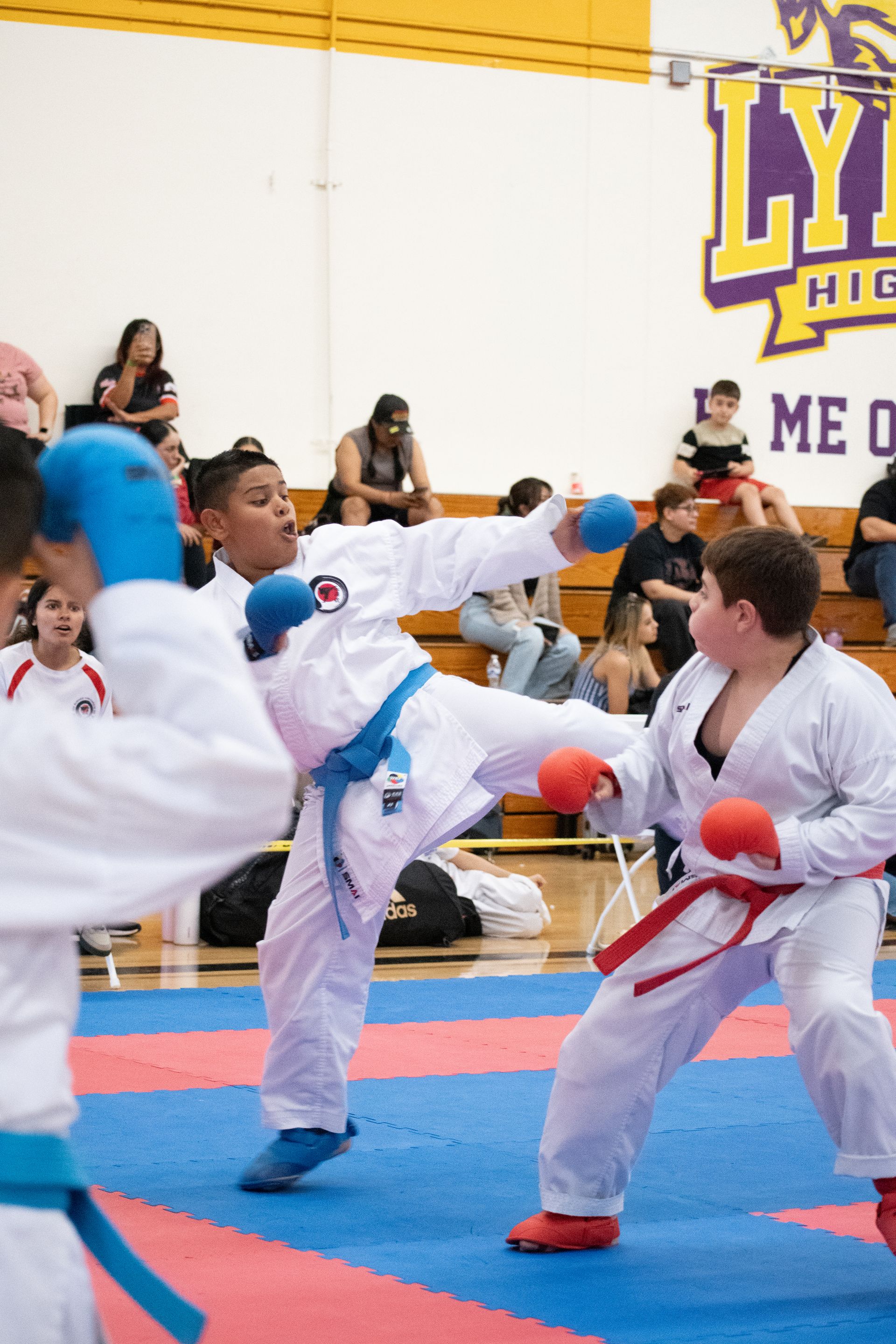 A group of kids are practicing martial arts in front of a sign that says lyr high school