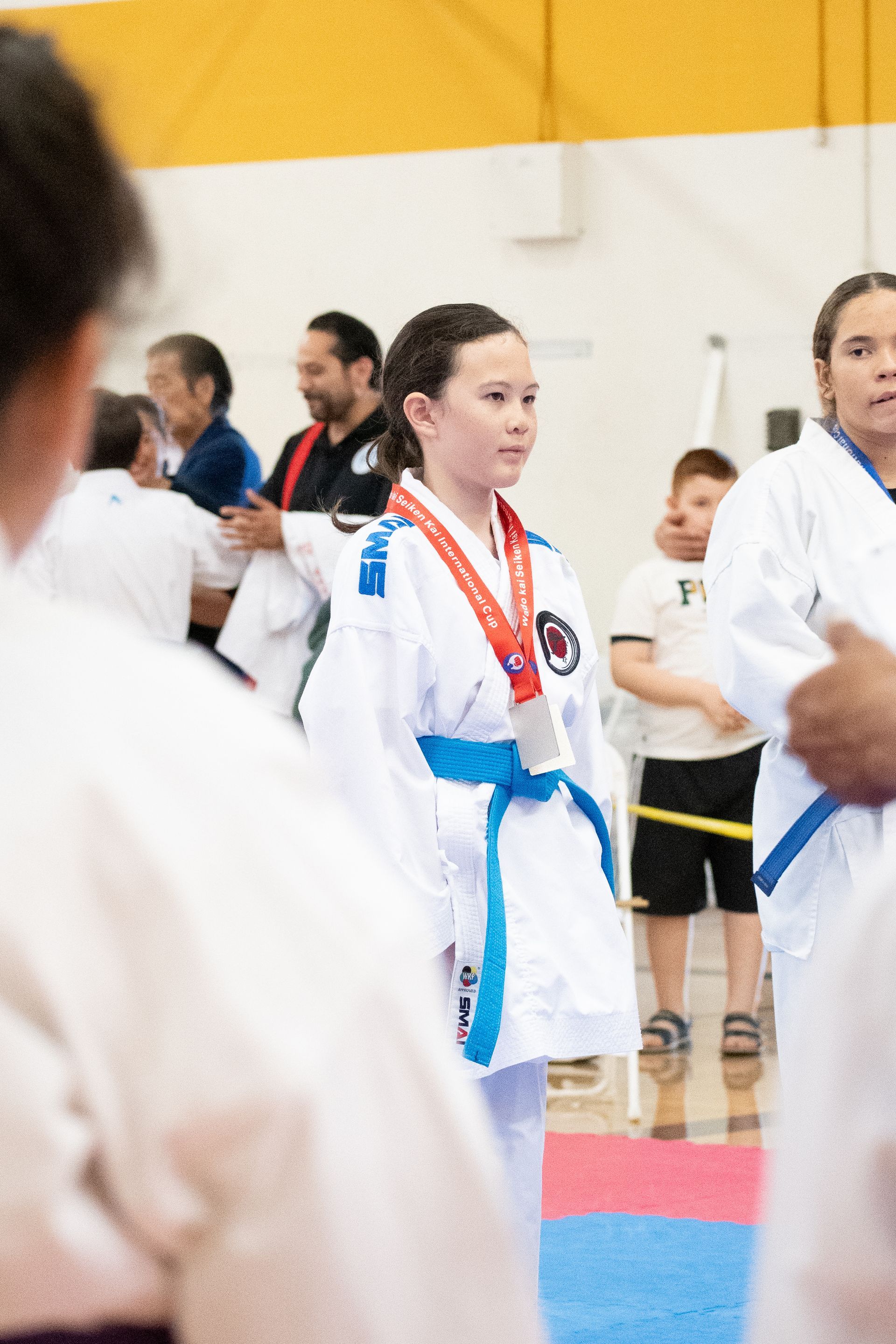 A girl in a karate uniform with a medal around her neck