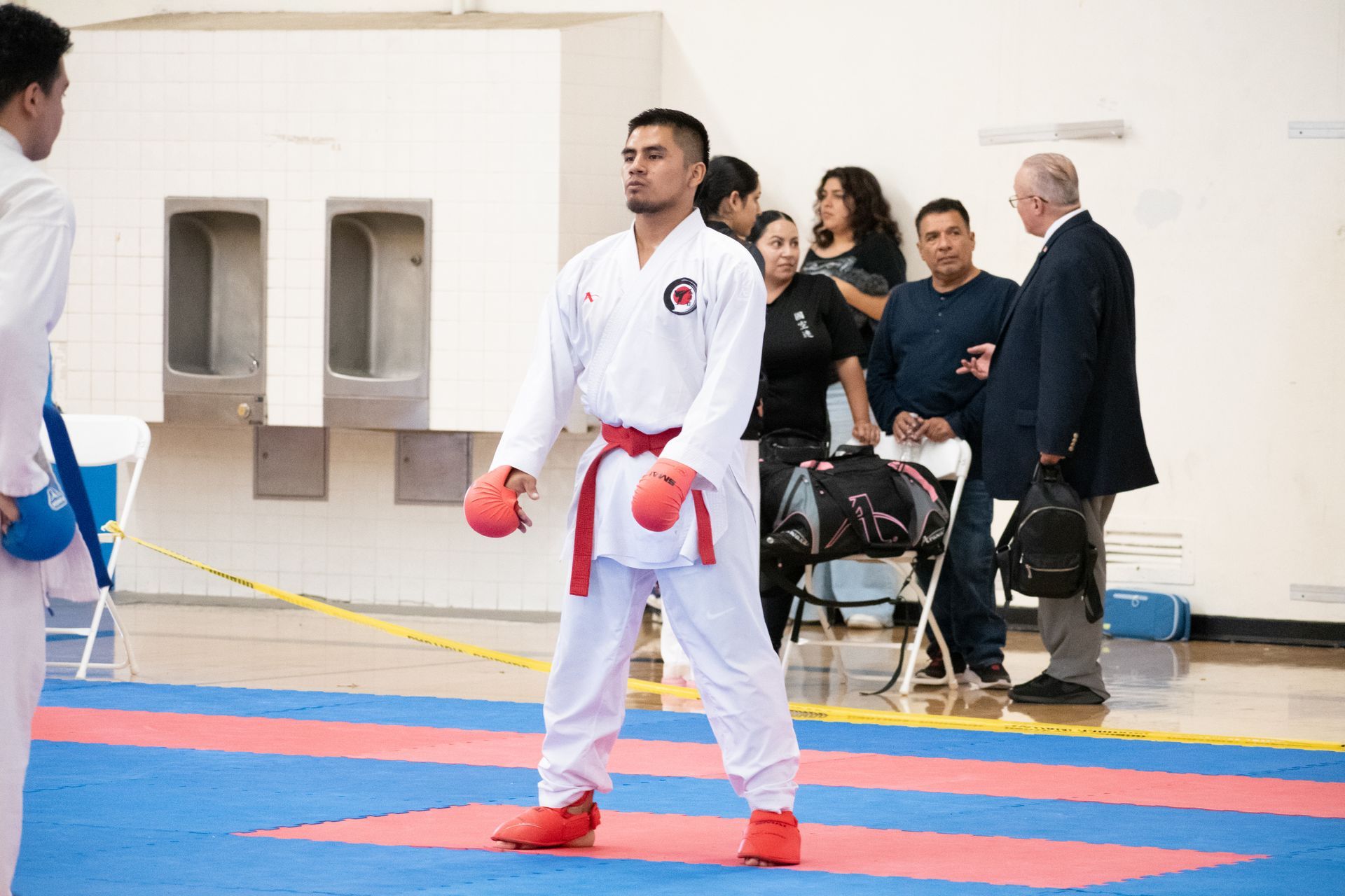 A man in a karate uniform is standing on a karate mat.