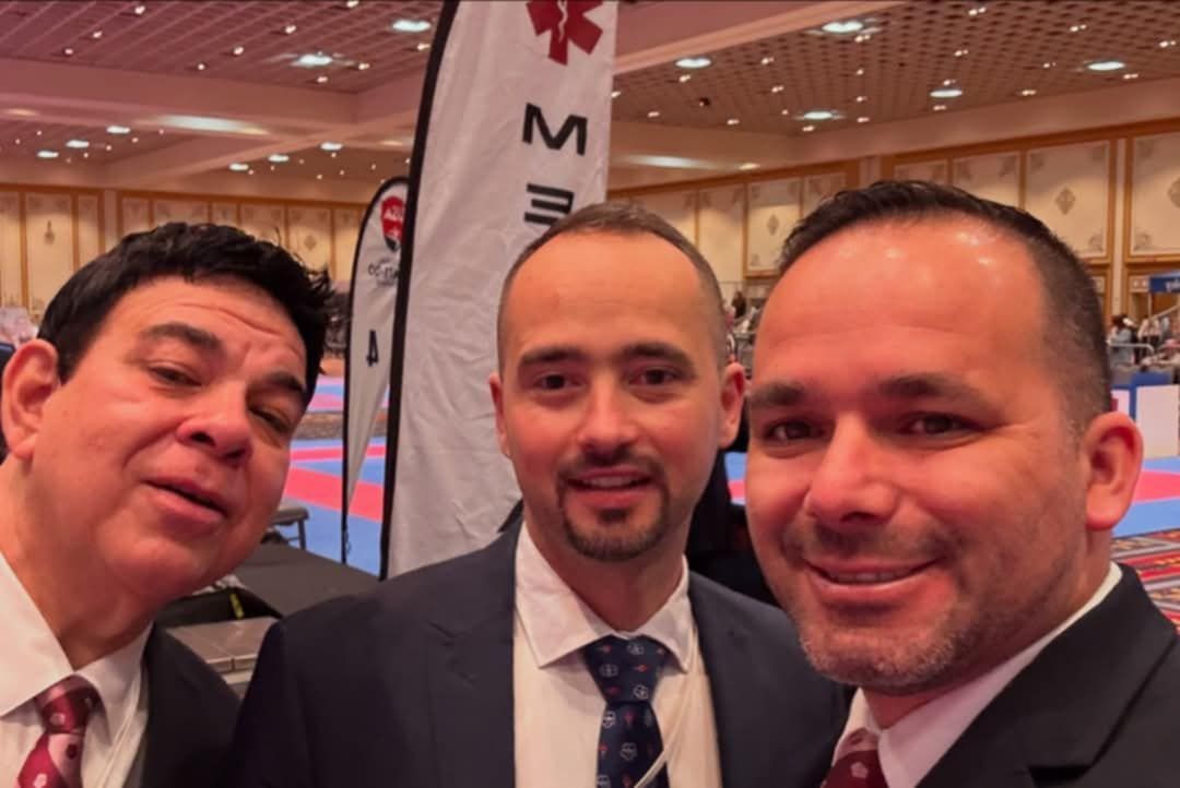 Three men are posing for a picture in front of a banner that says mm