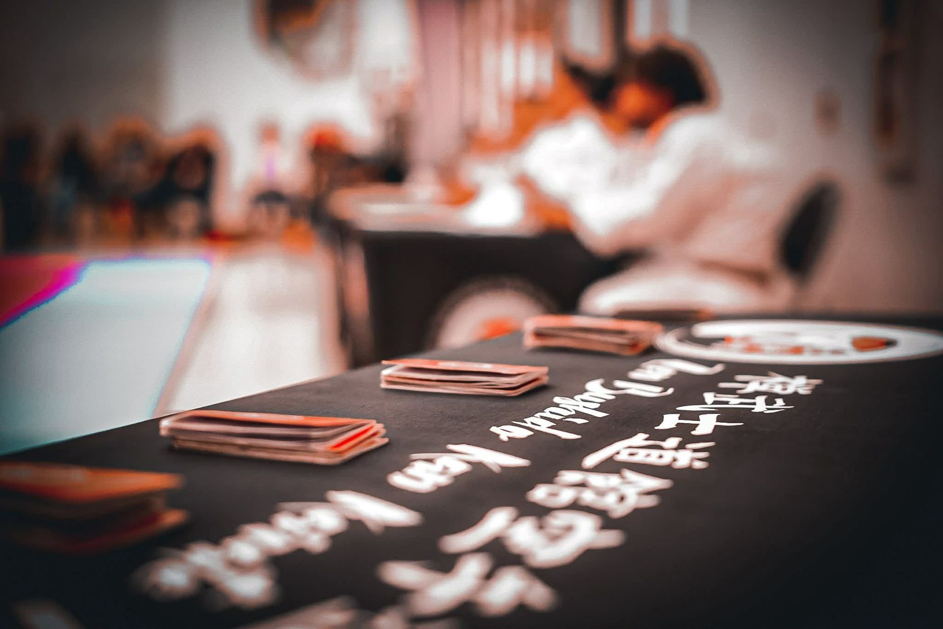 Stacks of cards on a table with white calligraphy. Blurry figures in white gis in background.