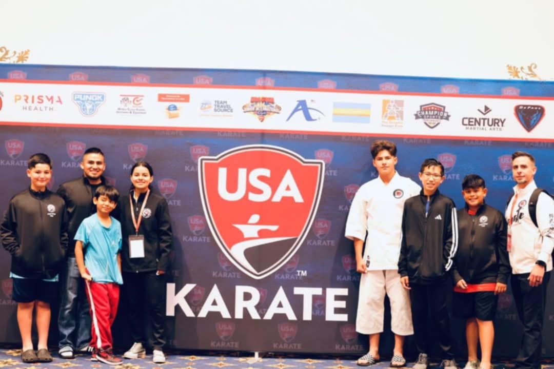 A group of people are standing in front of a usa karate sign.