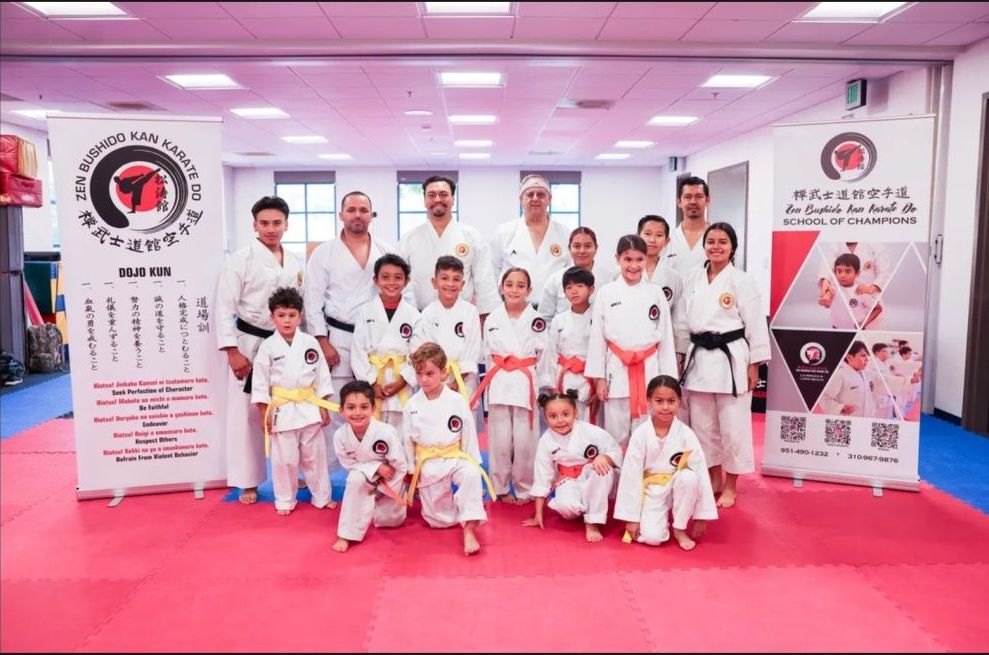 A group of people in karate uniforms are posing for a picture in a gym.