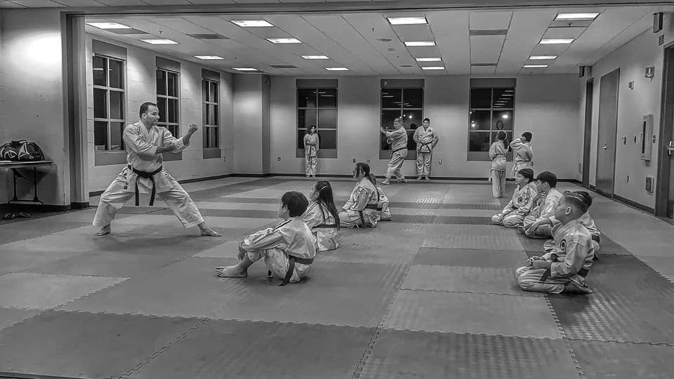 A group of children are practicing karate in a gym.