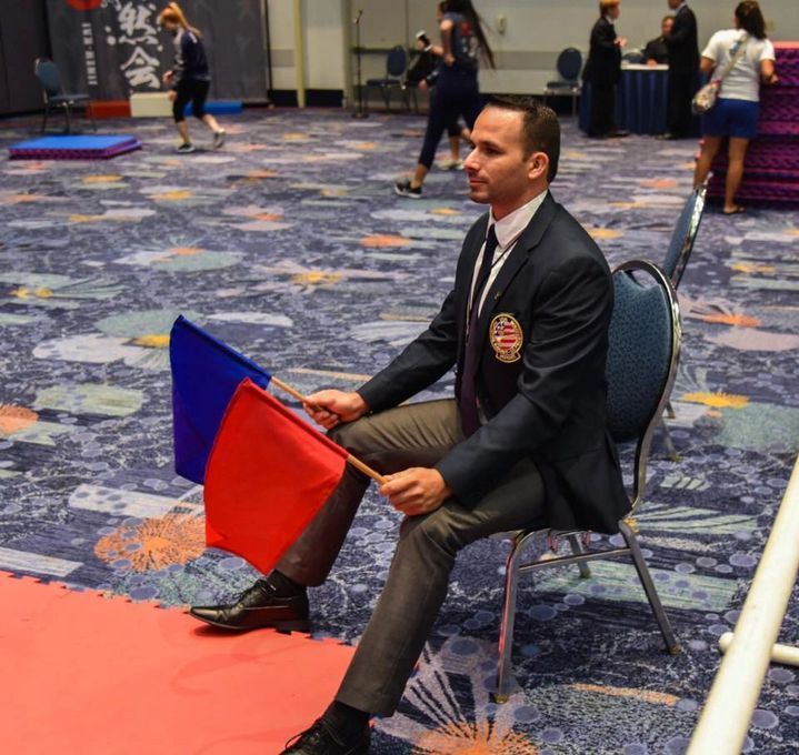 A man in a suit is sitting in a chair holding a red and blue flag