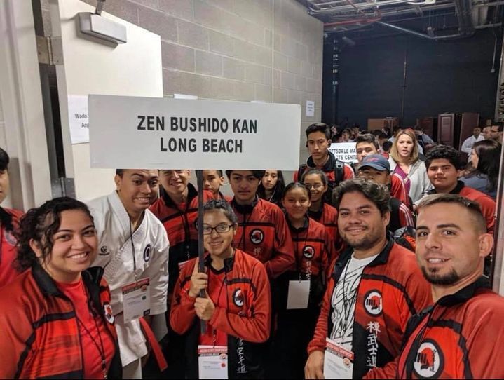 A group of people holding a sign that says zen bushido kan long beach