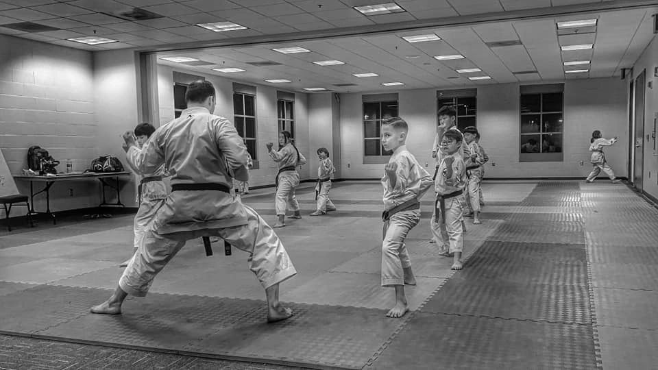 A group of people are practicing karate in a gym.