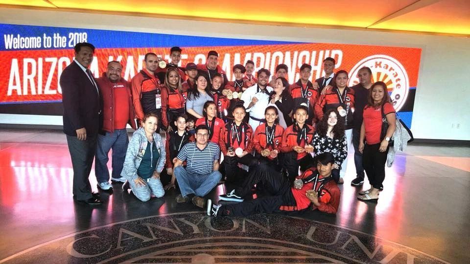 A group of people are posing for a picture in front of a sign that says welcome to the 2016 arizona championships.