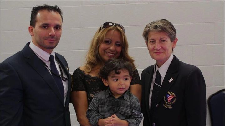 A man in a suit stands next to a woman holding a child